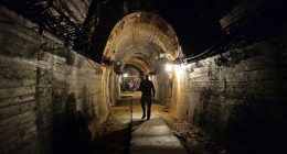 A man walks down a dimly lit tunnel.