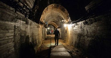 A man walks down a dimly lit tunnel.