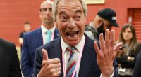 Nigel Farage giving a thumbs-up and raising his other hand.