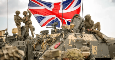 British soldiers with a Union Jack on a military vehicle.