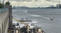 A barge on a river with a city skyline in the background.