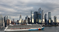 A shot of a cruise ship along the Hudson River in front of Hudson Yards and the Empire State Building in New York