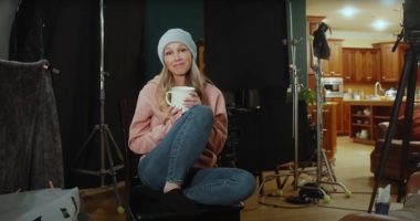 Woman holding a mug, sitting on a chair on a film set.