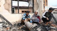 A family surveys the damage to their home after shelling.