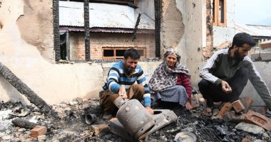 A family surveys the damage to their home after shelling.