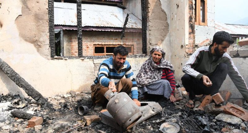 A family surveys the damage to their home after shelling.