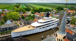 Aerial view of a large yacht passing through a canal in a Dutch town.