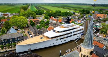 Aerial view of a large yacht passing through a canal in a Dutch town.