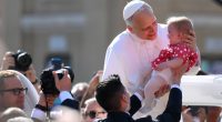 Pope Leo XIV holding a baby.