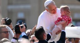 Pope Leo XIV holding a baby.