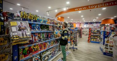 A masked employee stocking shelves in a toy store.
