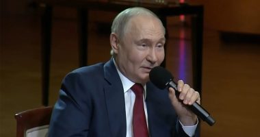 Vladimir Putin speaking into a microphone, stating that love is shown in ways beyond kissing and hugging.