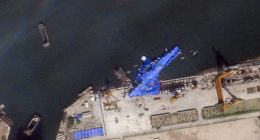 Satellite image of a North Korean warship covered in a blue tarp at a shipyard.