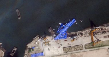 Satellite image of a North Korean warship covered in a blue tarp at a shipyard.