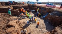 Archaeological dig site with workers excavating.