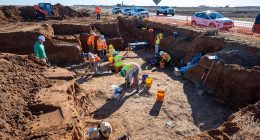 Archaeological dig site with workers excavating.
