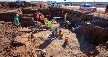 Archaeological dig site with workers excavating.