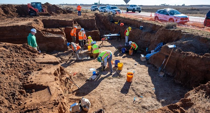 Archaeological dig site with workers excavating.
