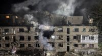 Apartment building damaged by a drone strike at night.