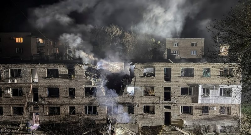 Apartment building damaged by a drone strike at night.
