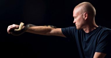 Man with hyper-immunity to snake venom holding a water cobra.