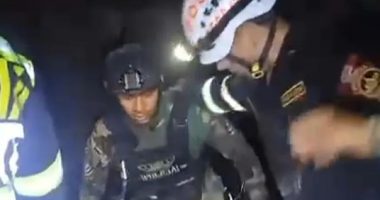 Security personnel assisting a person in a dark setting.