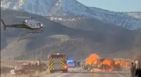Rescue workers and a helicopter at the scene of a fiery vehicle collision.