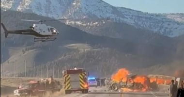 Rescue workers and a helicopter at the scene of a fiery vehicle collision.