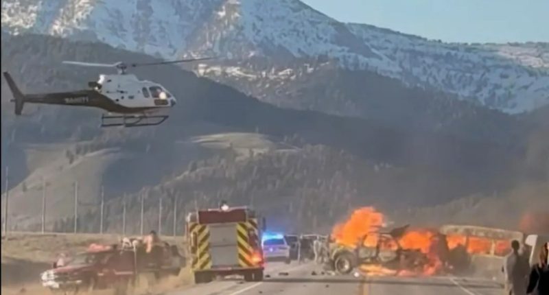 Rescue workers and a helicopter at the scene of a fiery vehicle collision.