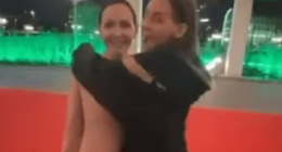 A woman embracing a life-sized cutout of the mayor on a red carpet.