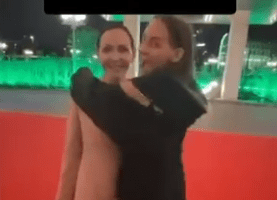 A woman embracing a life-sized cutout of the mayor on a red carpet.