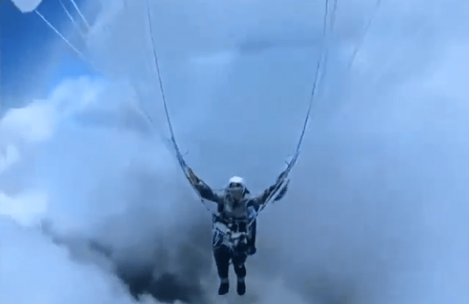 Person paragliding in clouds.