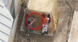 Overhead view of two boys behind a covered object, one appearing to hold a gun.