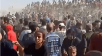 Large crowd of people gathered, many on horseback or camels in the background.
