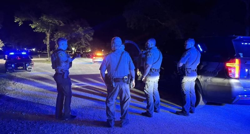Police officers at a night crime scene.