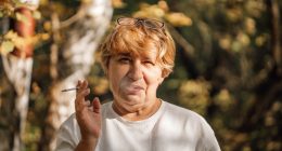 Senior woman smoking a cigarette in a forest.