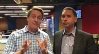Two TV weathermen in a newsroom.