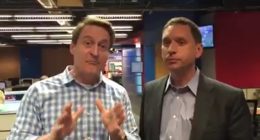 Two TV weathermen in a newsroom.