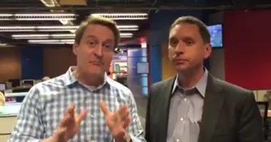 Two TV weathermen in a newsroom.