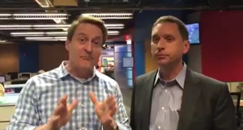 Two TV weathermen in a newsroom.