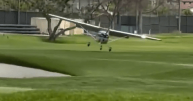 Small plane landing on a golf course.