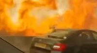 Cars driving on a highway next to a large wildfire.