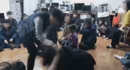 A person interacting with a group of children sitting on the floor.