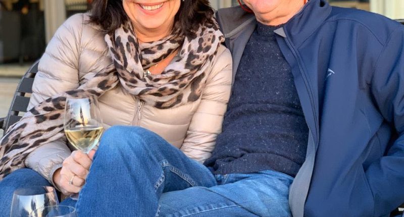 Alan and Karen Carter sitting together outdoors with wine.