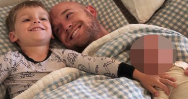 Father and two children lying in bed.