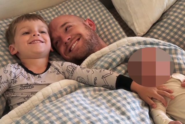 Father and two children lying in bed.