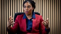 Photo of Kemi Badenoch in a red suit jacket, giving an interview.