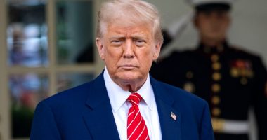Donald Trump in a blue suit and red tie outside the White House.