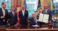 President Trump signing executive orders in the Oval Office with White House staff.