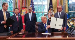 President Trump signing executive orders in the Oval Office with White House staff.